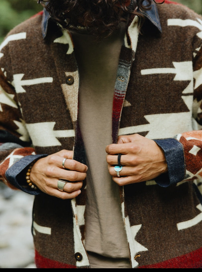 Close-up of hands buttoning the Peguche Jacket, handwoven dark brown and cream Andean wool